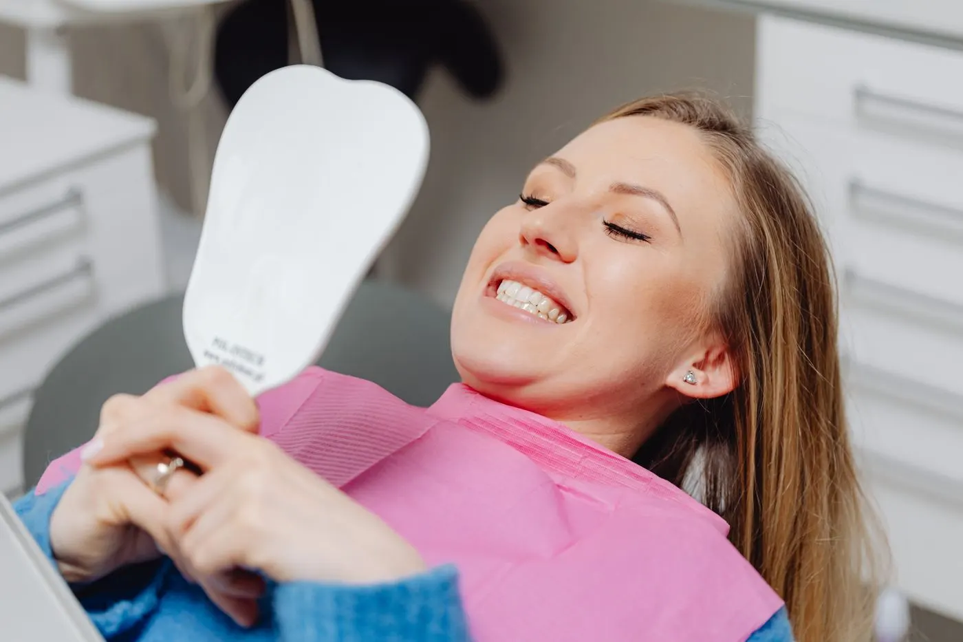 Paciente sorrindo ao espelho após consulta odontológica