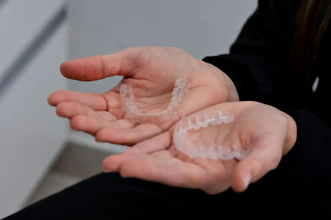 Alinhadores transparentes do tipo Invisalign nas mãos de uma paciente